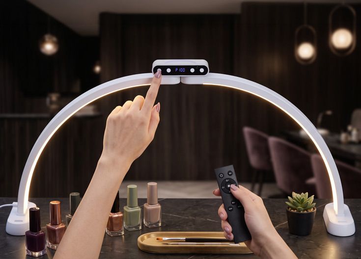 One hand presses the control panel on top of the white Half-Moon Light while the other hand holds the remote.